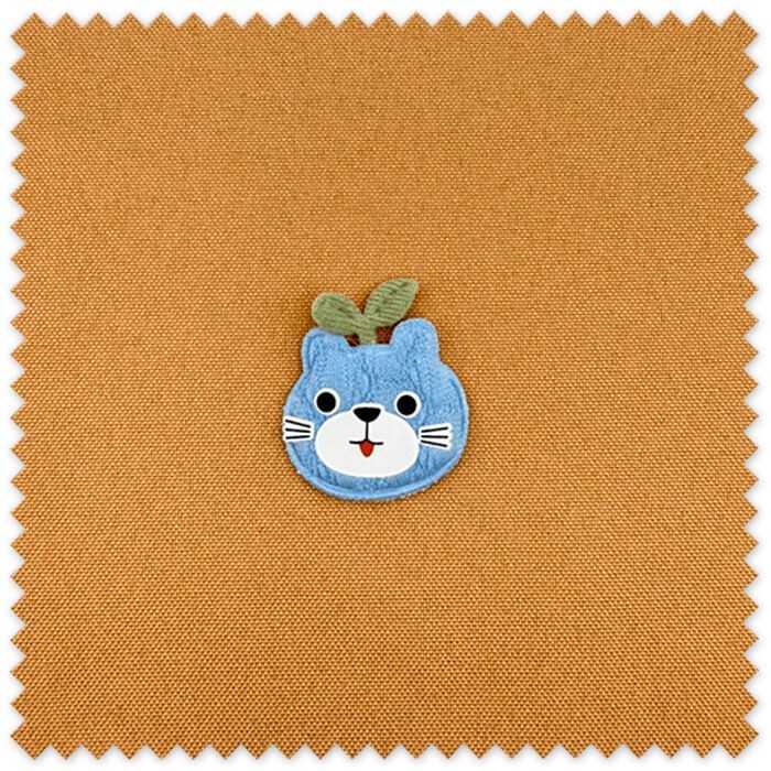 Detalle del parche manzana con cara azul bordado